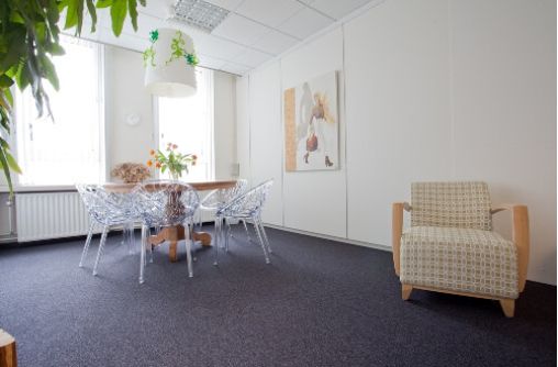 spreekkamer met ronde houten tafel en fauteuil